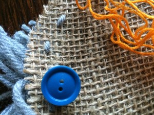 Use button sewn in contrast thread over yarn knots back of pom-pom on stocking